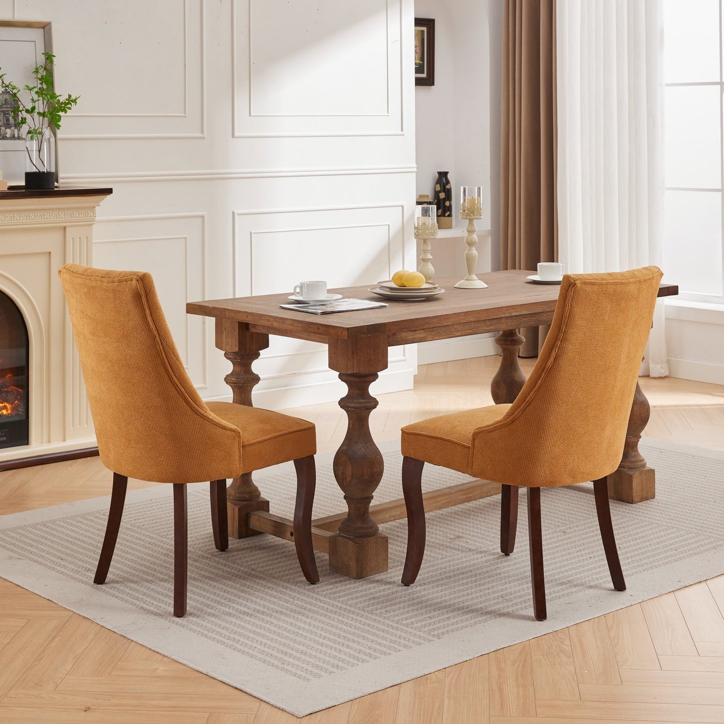 Two mustard yellow upholstered dining chairs with wooden legs next to a rustic wood dining table