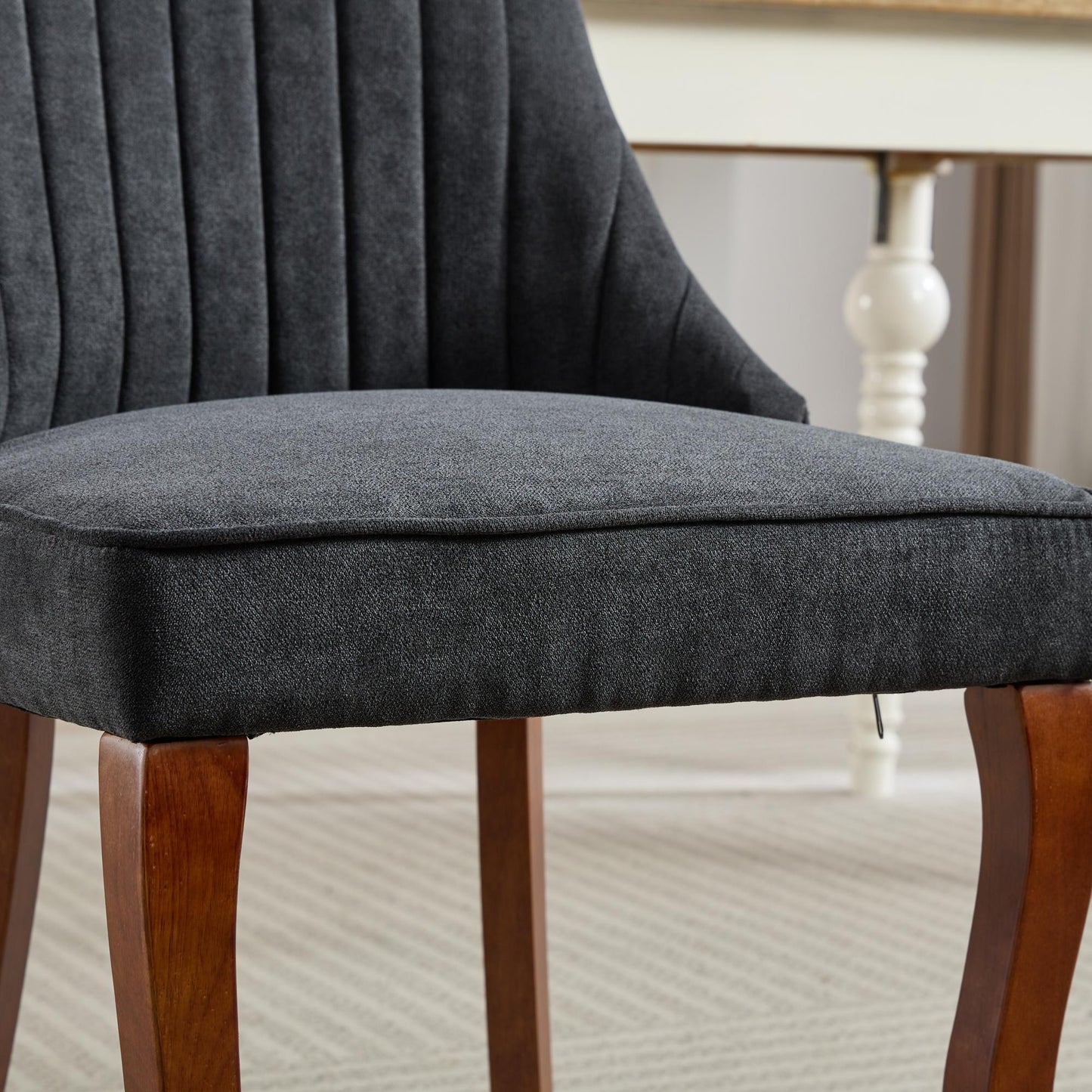 Dark grey upholstered dining chair with channel tufted back and wooden legs