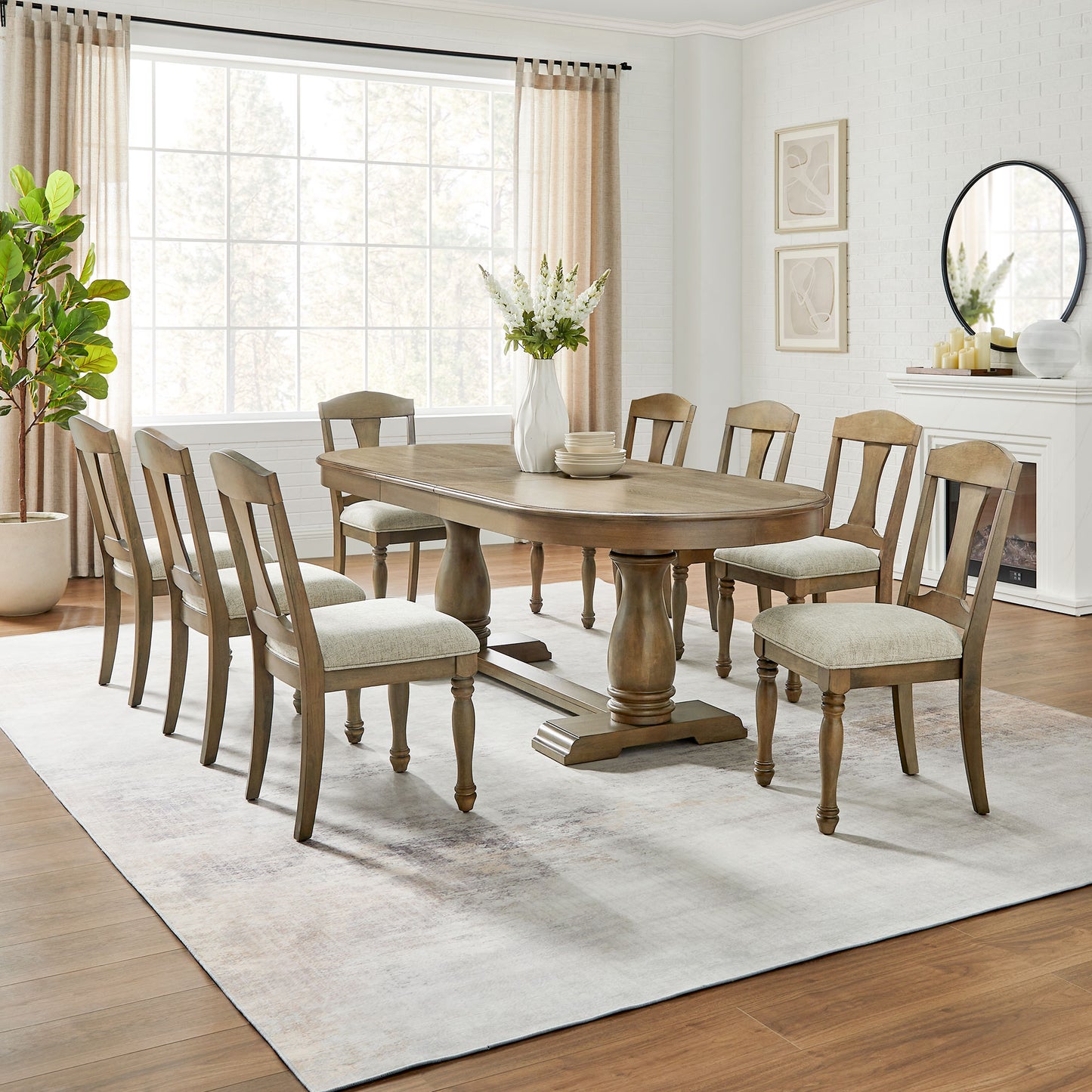Oval pedestal dining table with eight upholstered chairs in a bright dining room