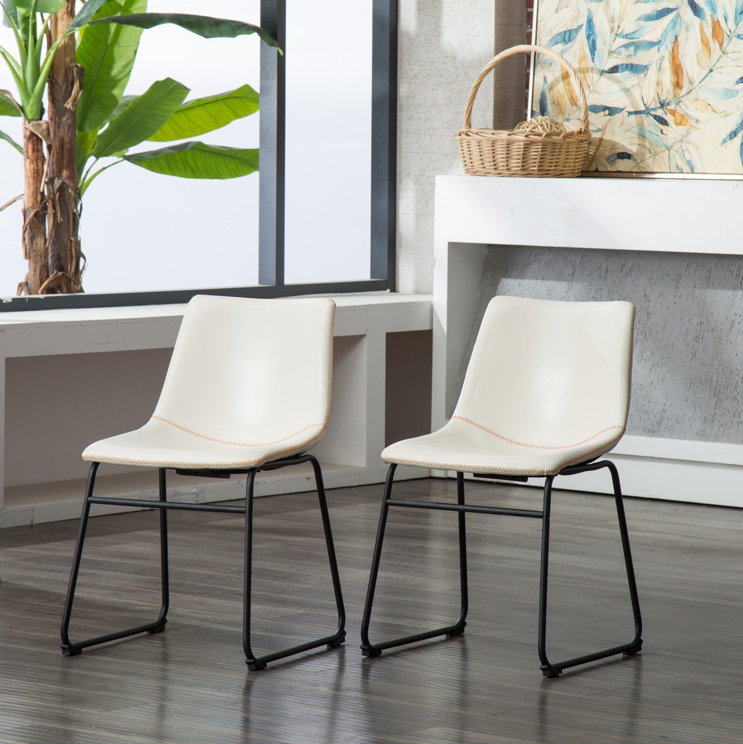 Two cream faux leather dining chairs with black metal legs