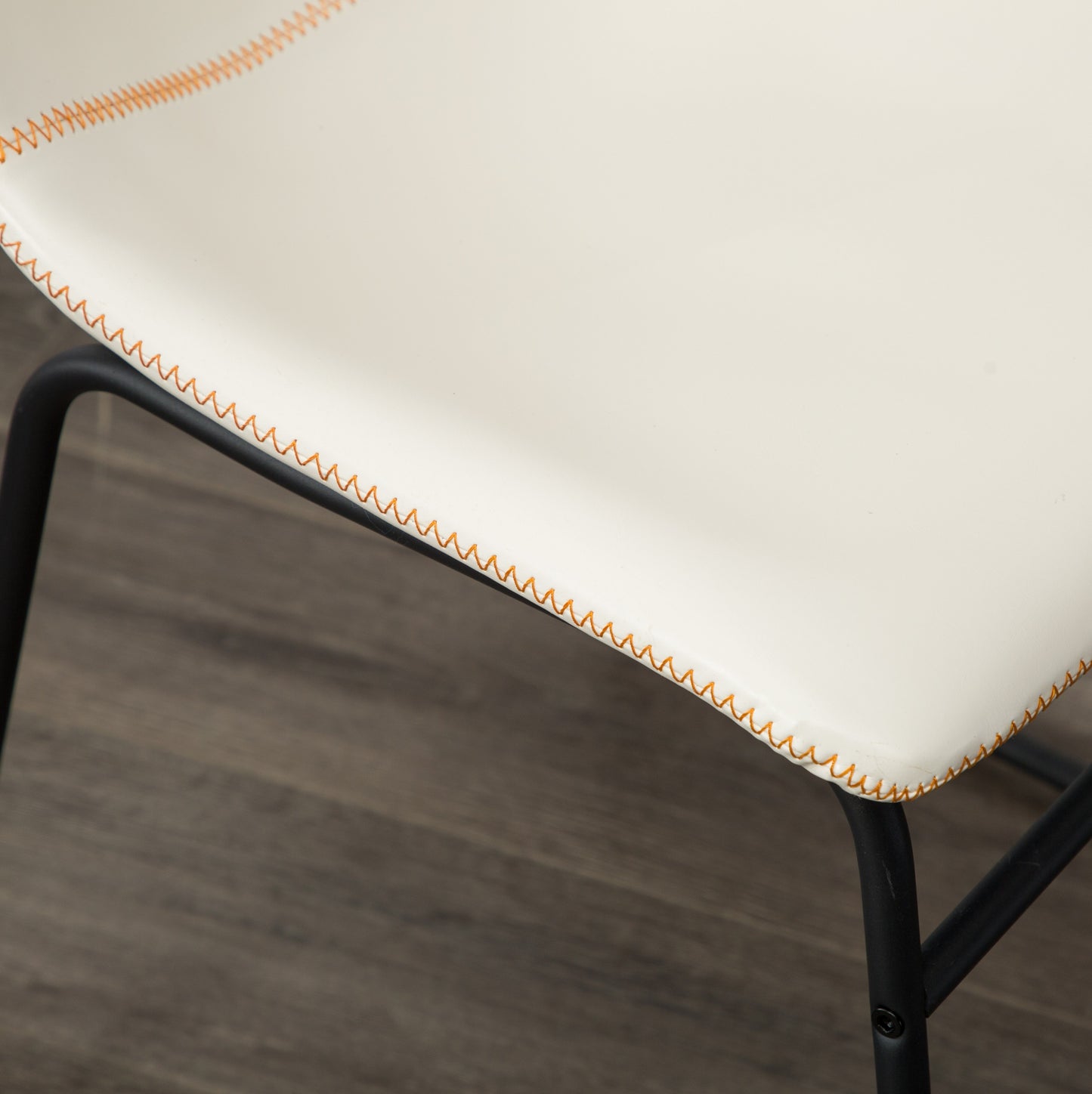 Cream faux leather dining chair with orange stitching detail and black metal legs