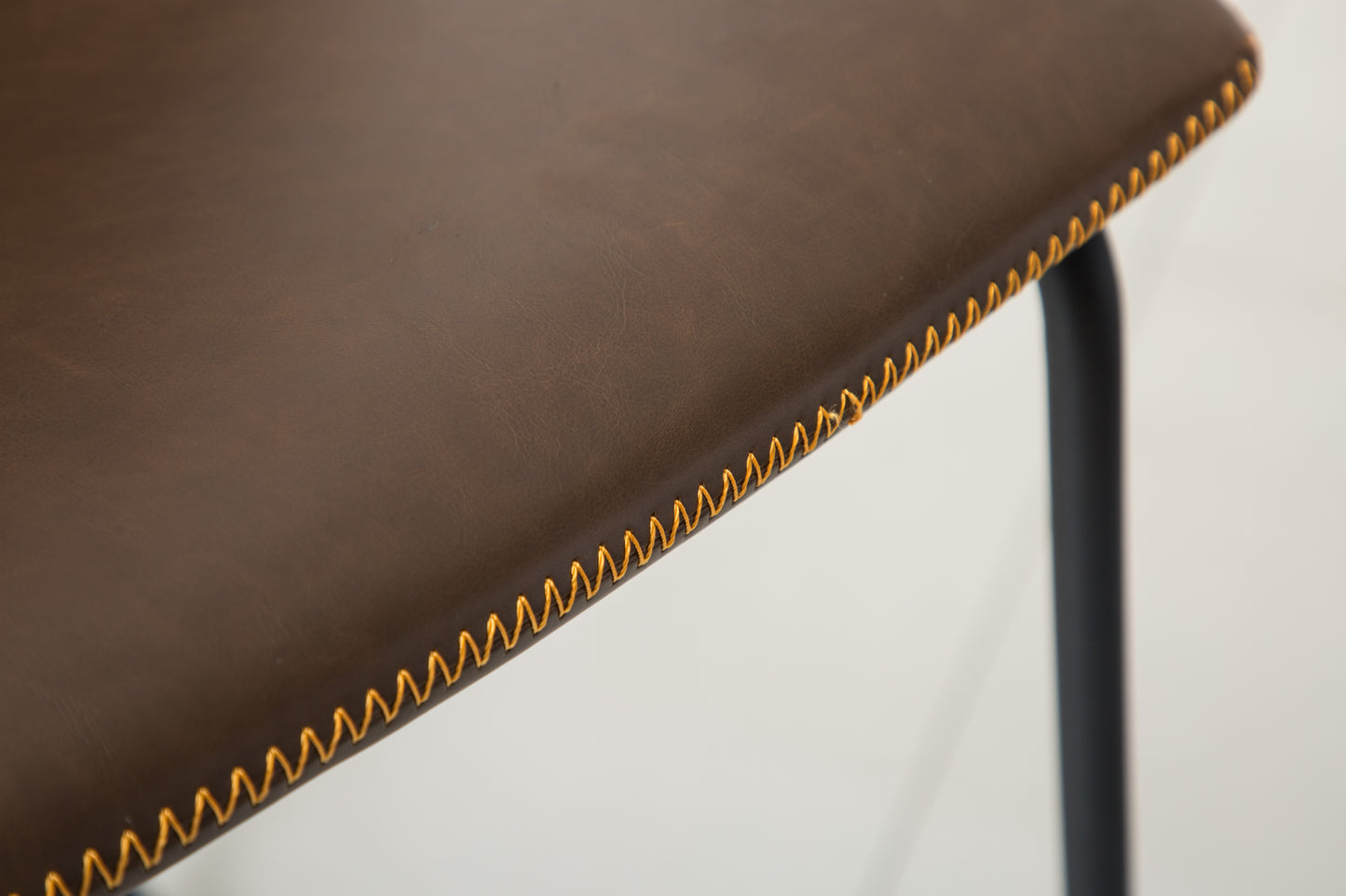 Dark brown faux leather bar stool seat with visible golden stitching detail