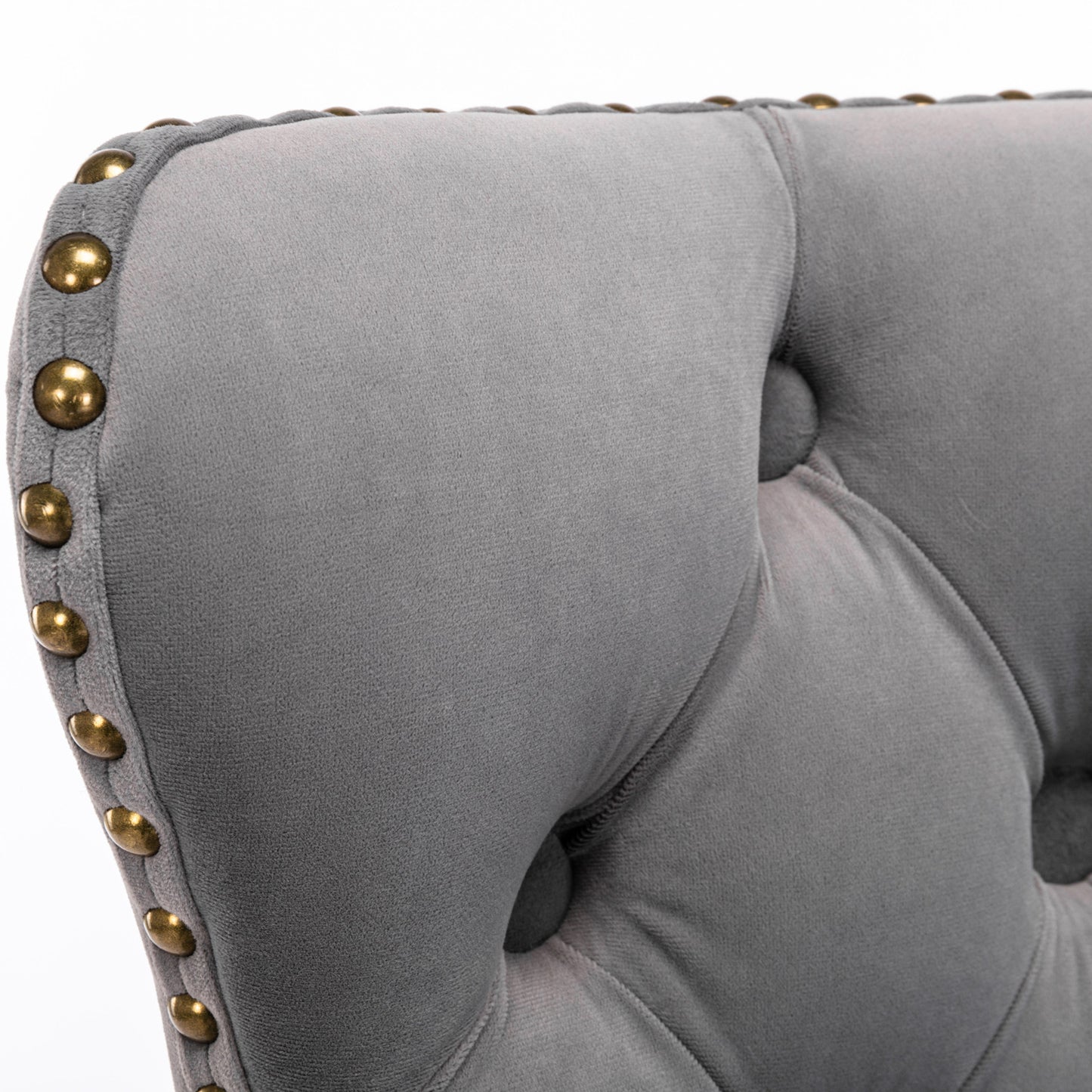 Closeup of a grey velvet chair with tufted buttons and brass nailhead trim