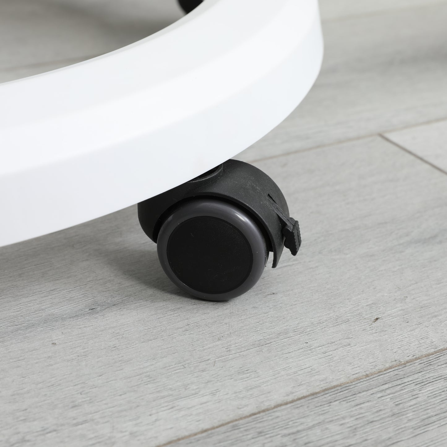 Black swivel caster wheel with grey rim on a white office chair base