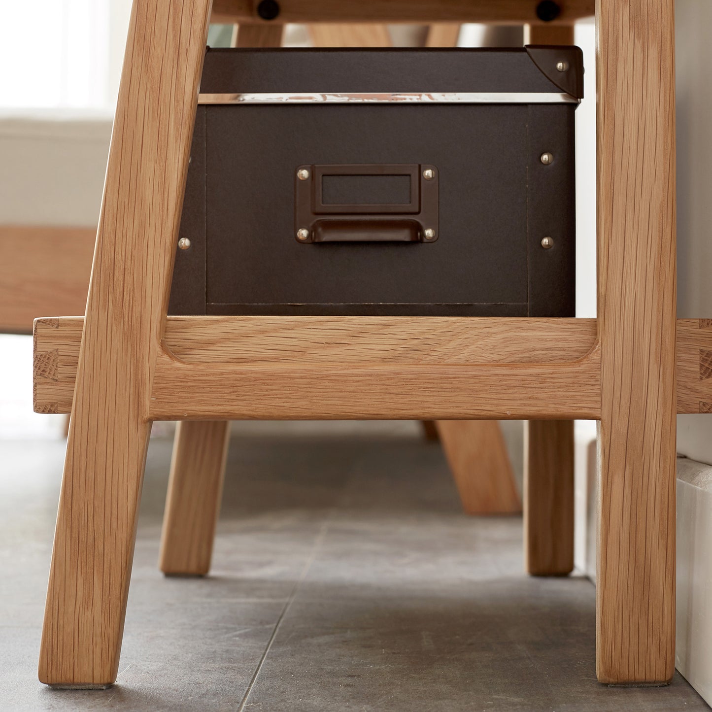 Dark brown faux leather storage box with metal accents placed under a wooden desk for home organization