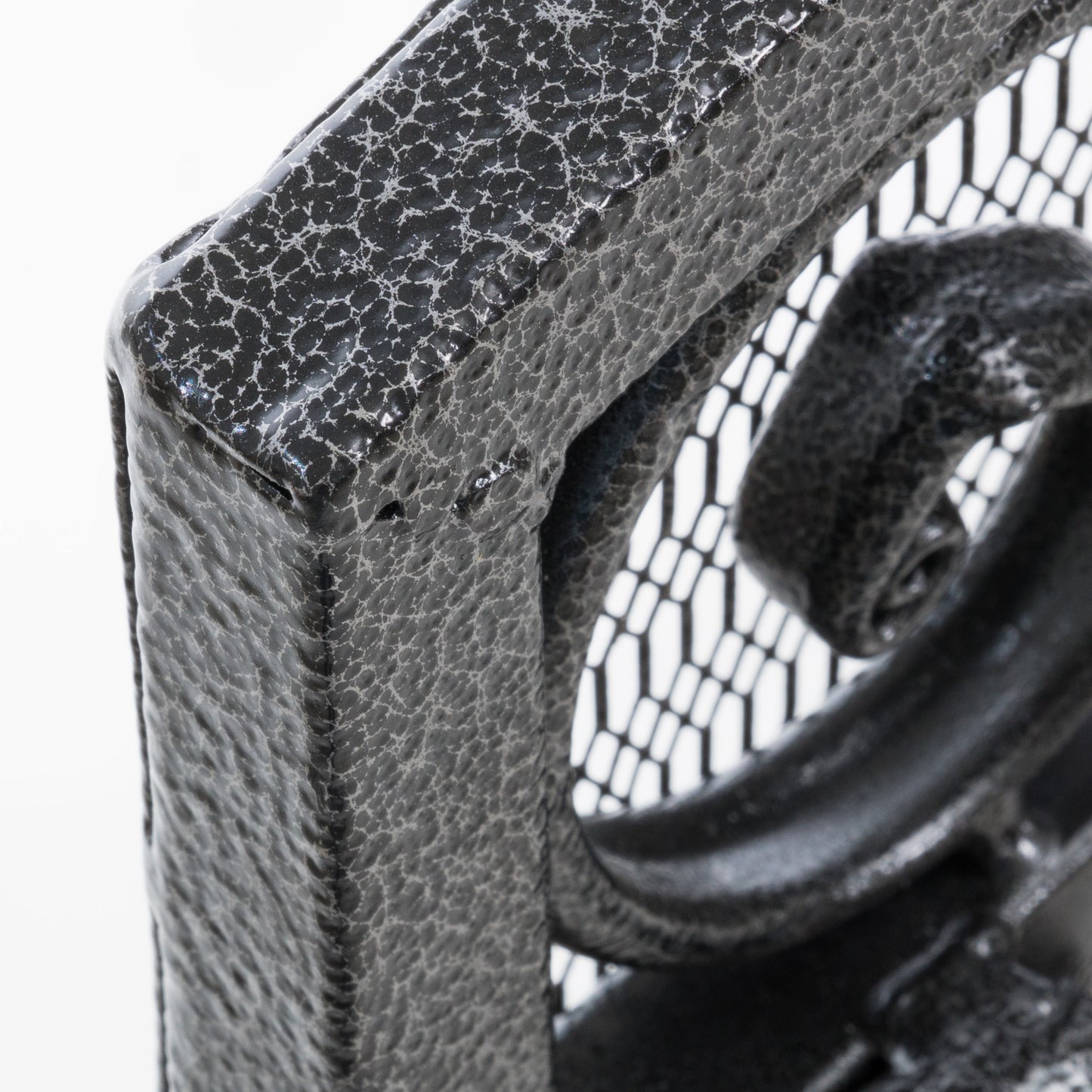 Closeup of a textured black metal scrollwork corner on a table