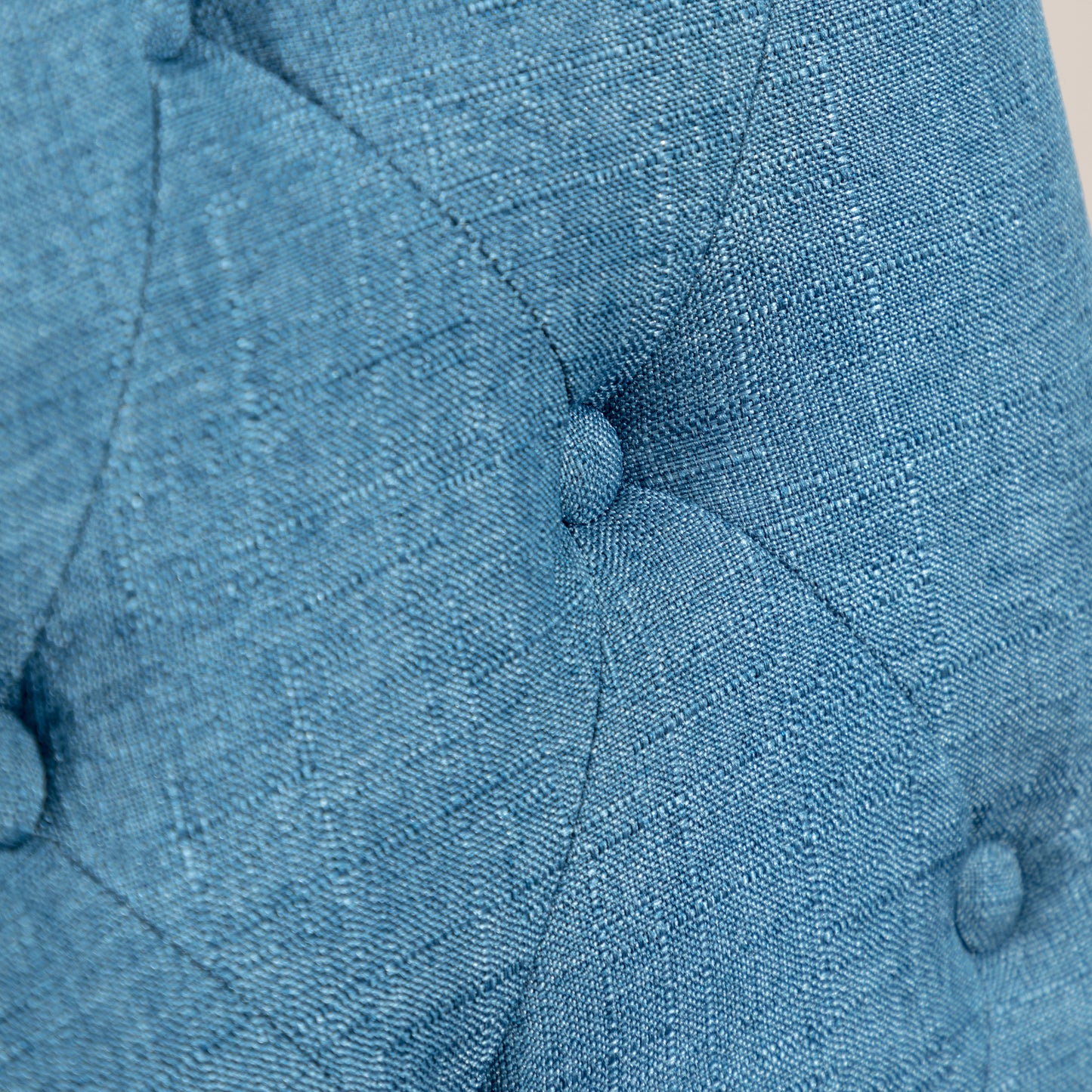 Closeup of textured teal fabric with button tufting