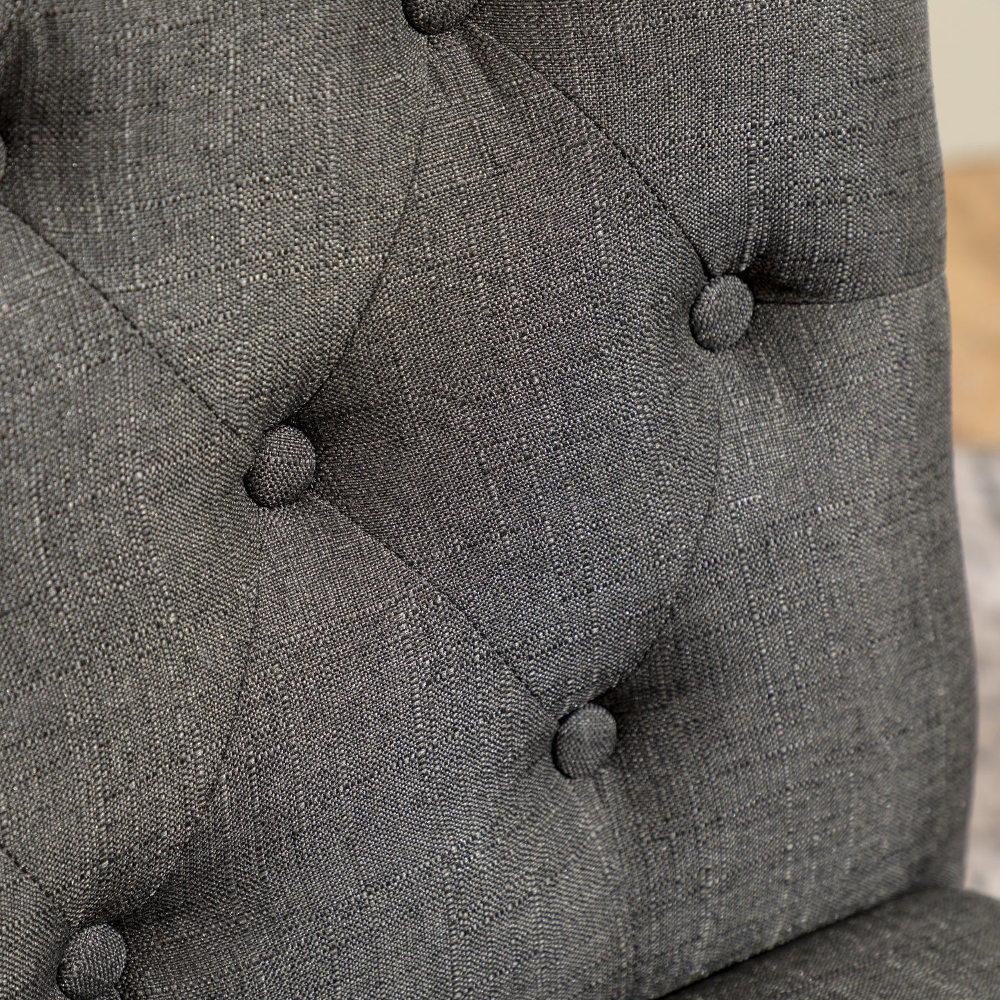 Closeup of tufted charcoal grey fabric upholstery with visible texture