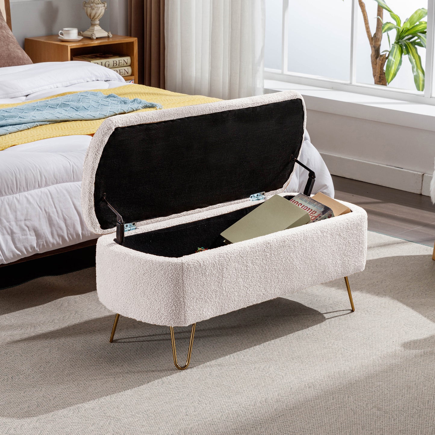 Cream boucl storage ottoman with gold hairpin legs open to reveal books inside