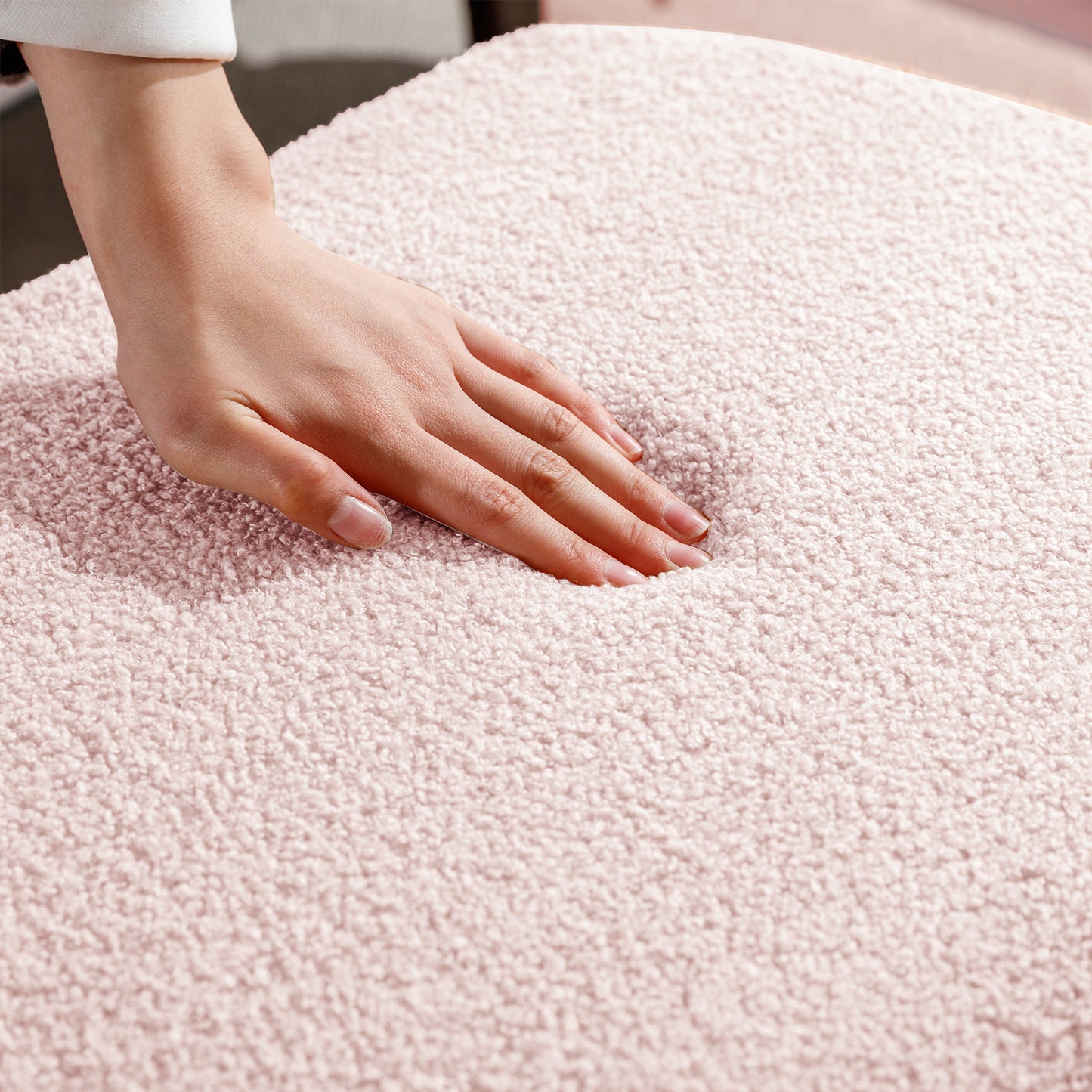 Closeup of a hand pressing into a soft blush pink teddy bear fabric