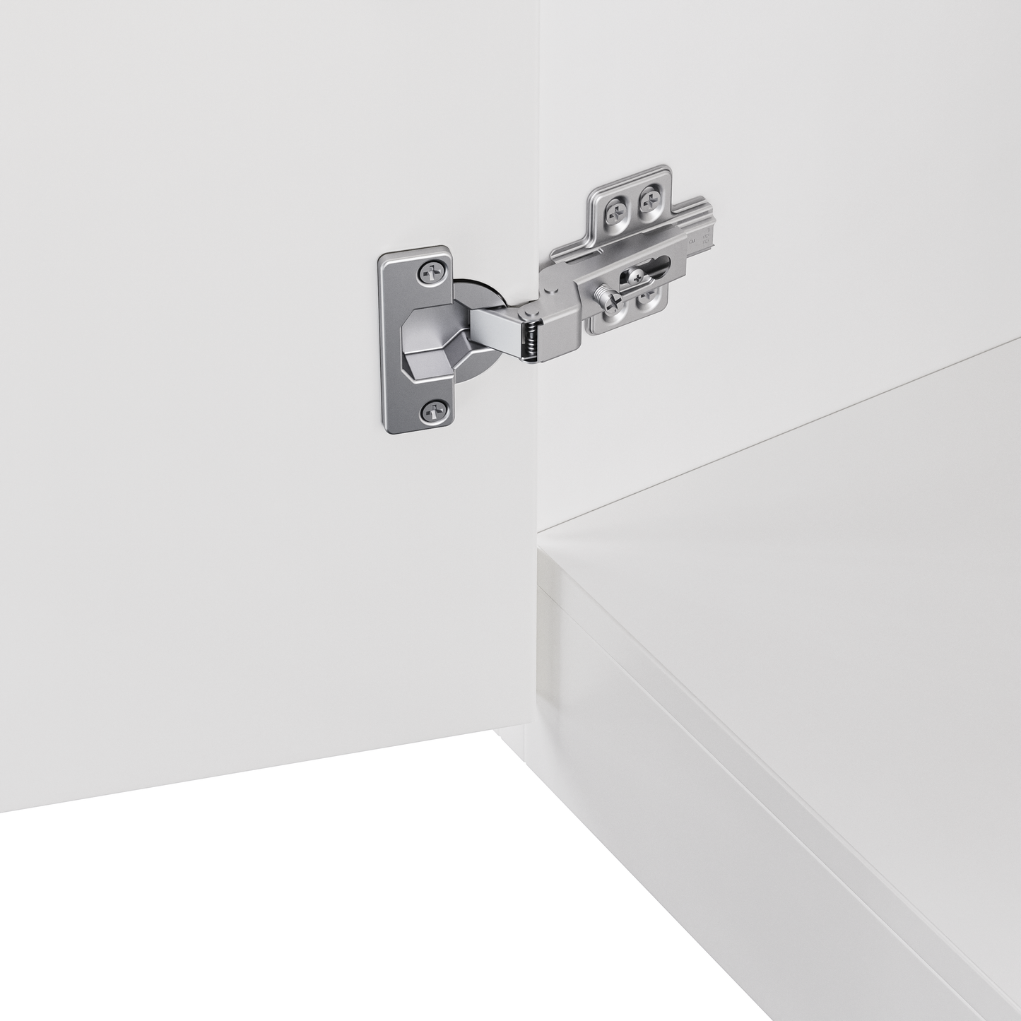Closeup of a brushed metal cabinet hinge with visible screws on a white door