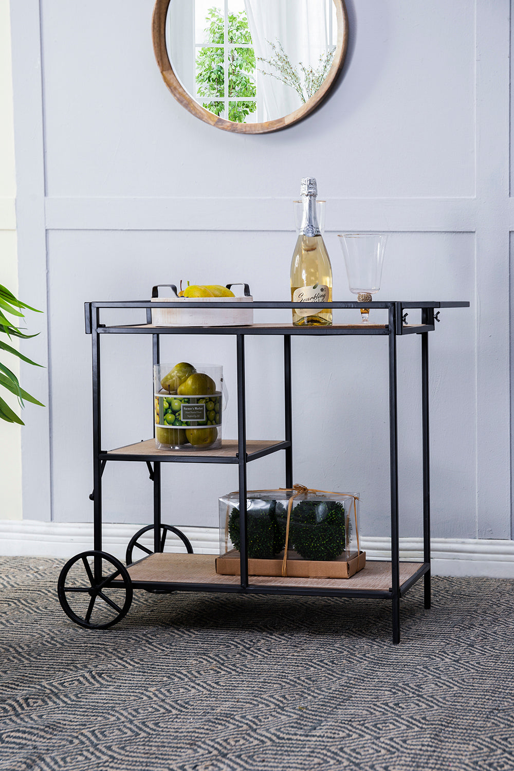 Black metal bar cart with two shelves holding decorative items