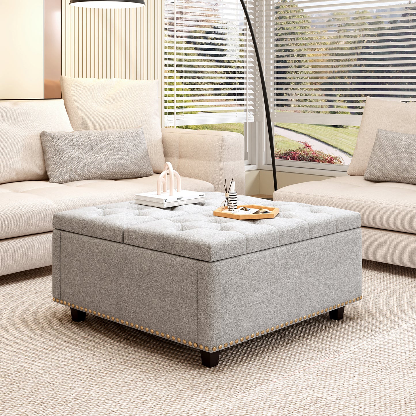 Gray fabric storage ottoman with button tufting and nailhead trim