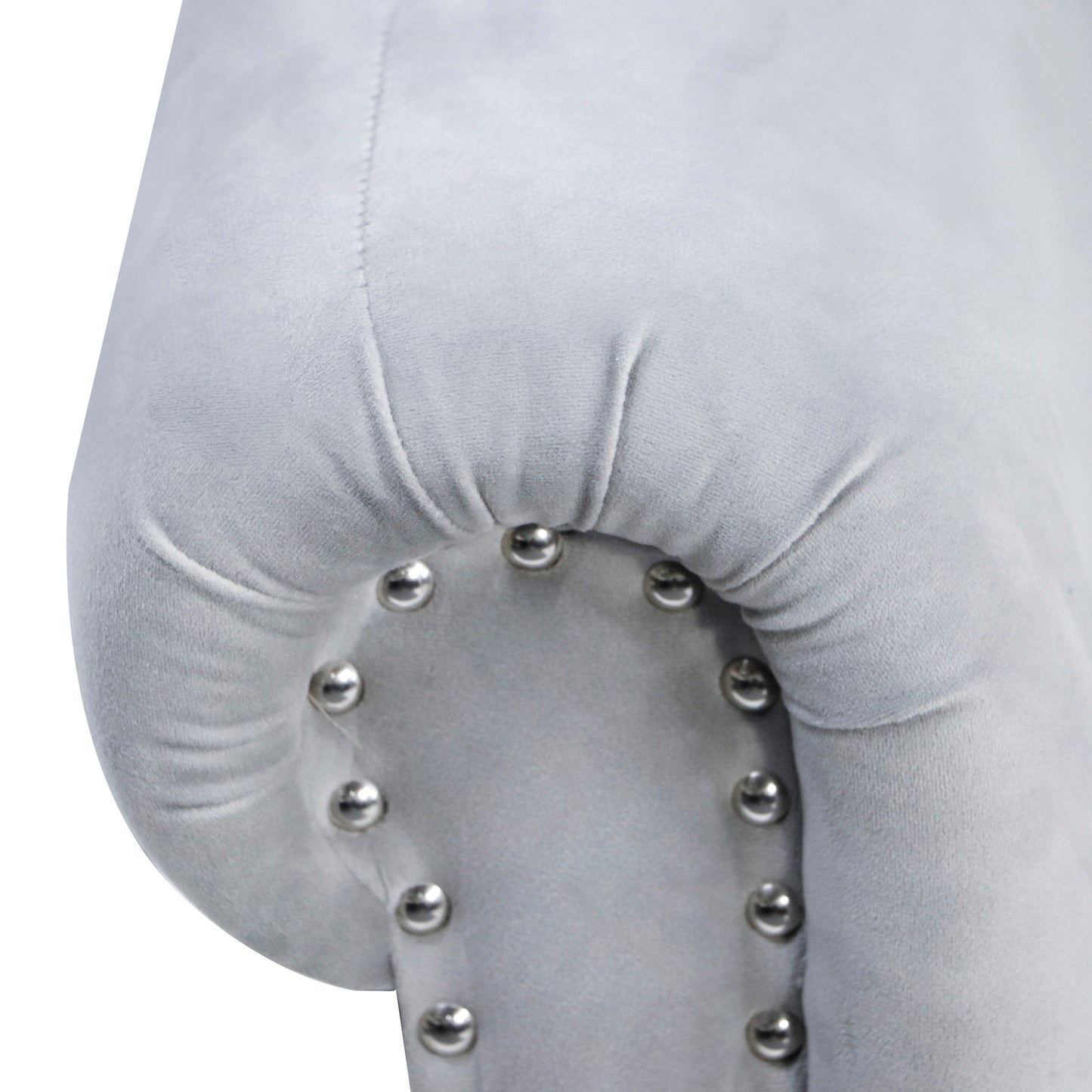 Light gray velvet armchair detail with tufted accents and silver nailhead trim
