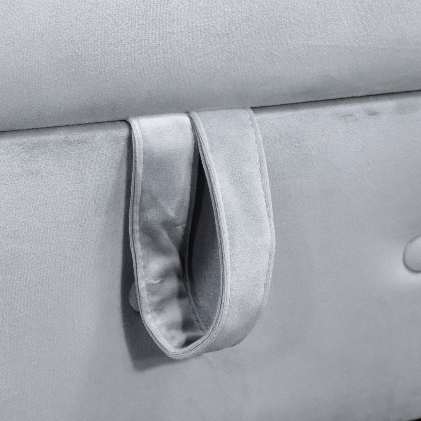 Closeup of grey velvet fabric storage ottoman with attached fabric pull tab