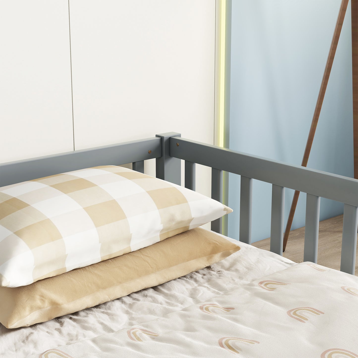 Grey wooden crib railing with beige plaid and solid pillows
