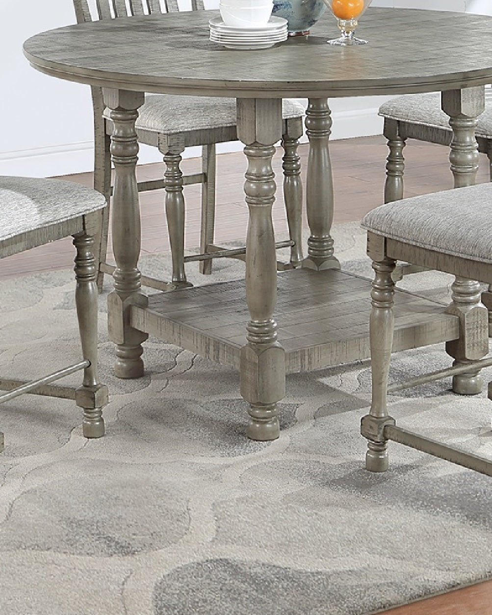 Round grey wood dining table with turned legs and upholstered stools