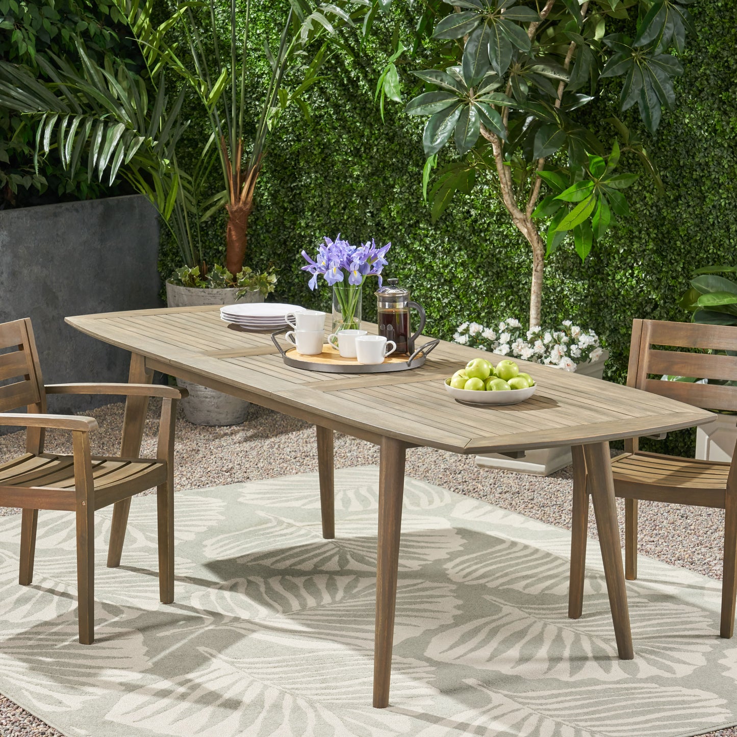 Wooden outdoor dining table and chairs with a tray of coffee cups and fruit