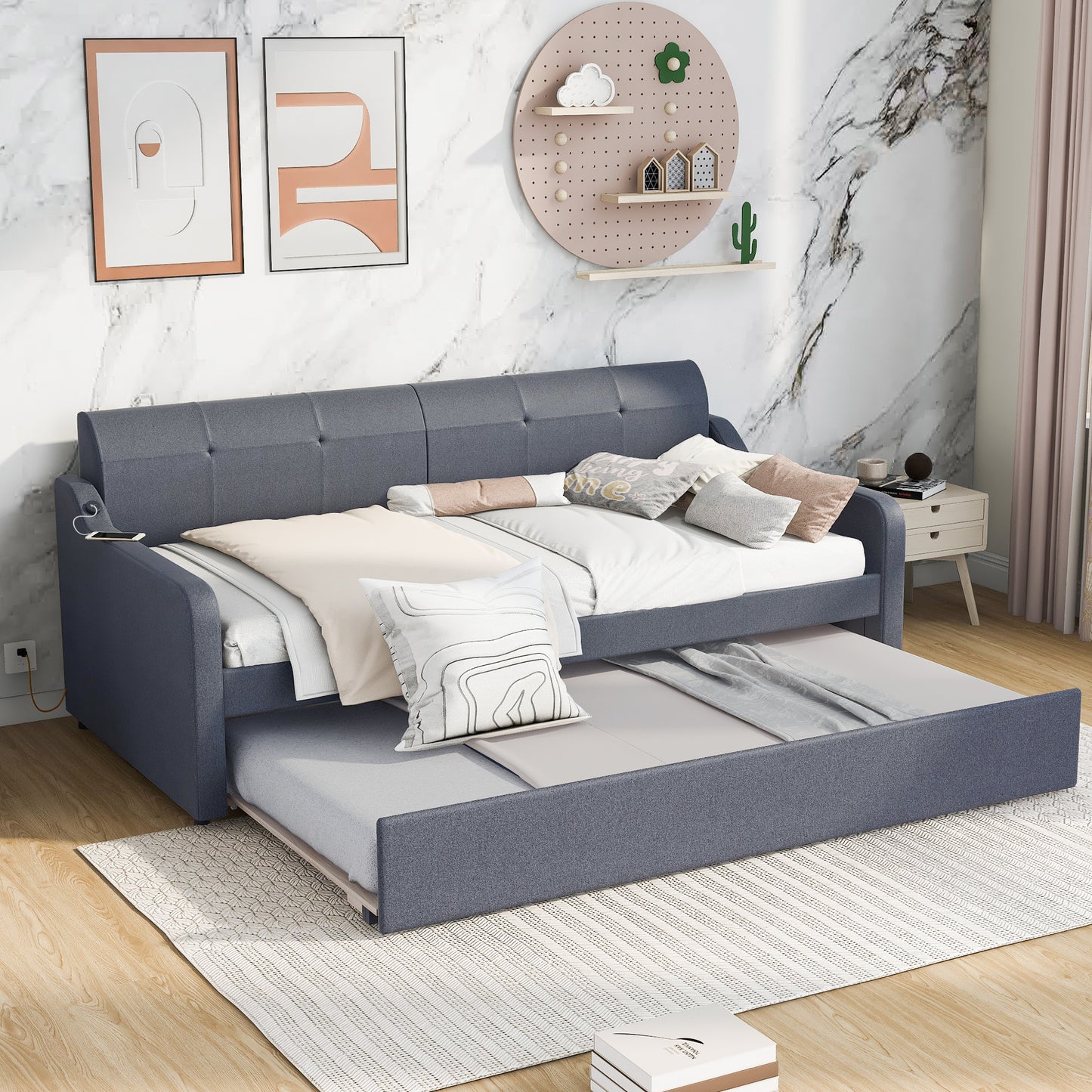 Gray upholstered daybed with trundle pulled out and made up with bedding and pillows