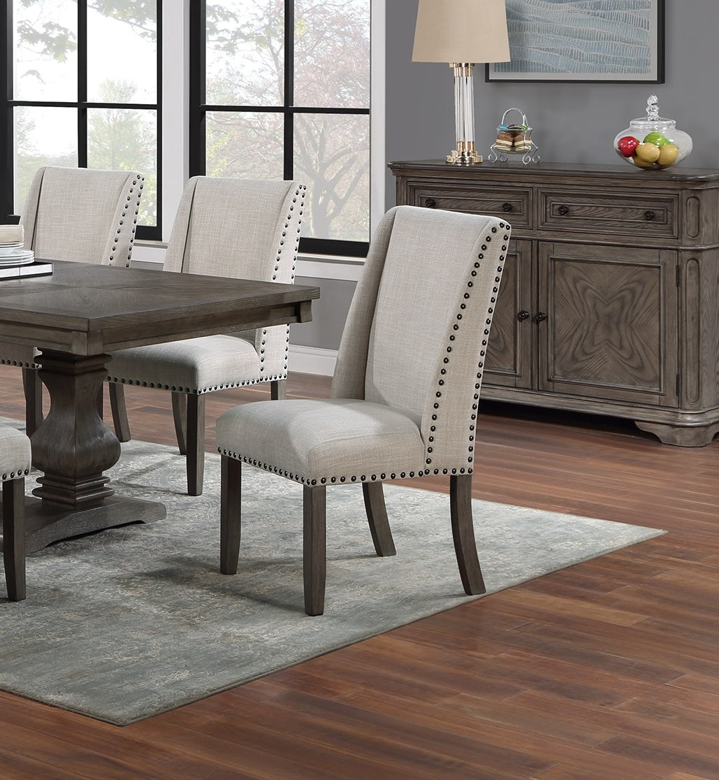 Upholstered dining chair in light beige fabric with nailhead trim detail and dark wood legs