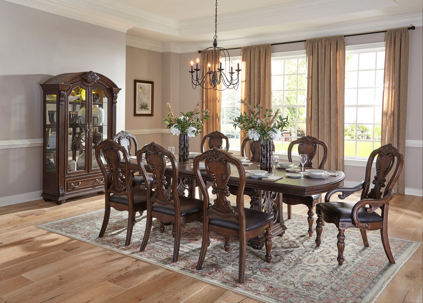 Ornate dark wood dining table set with carved chairs and a glass china cabinet