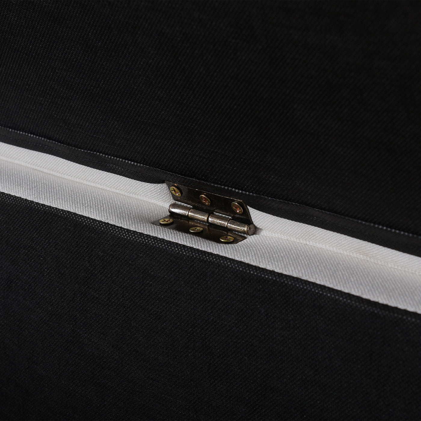 Closeup of a black fabric storage ottoman hinge
