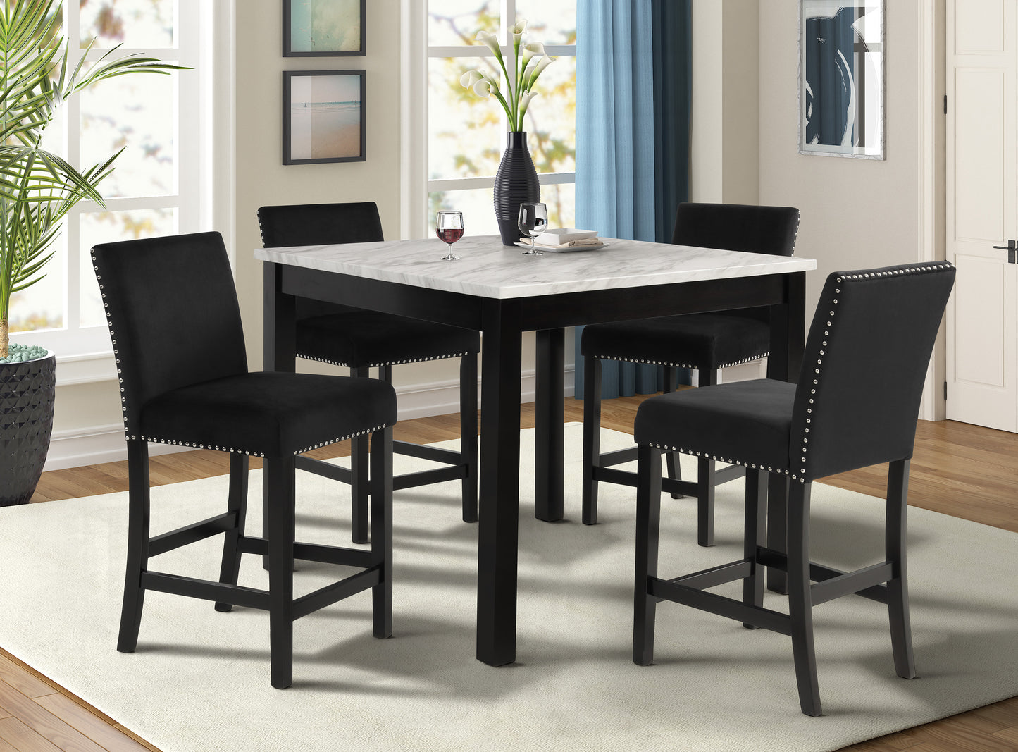 Black velvet bar stools with silver nailhead trim surrounding a white marble pub table