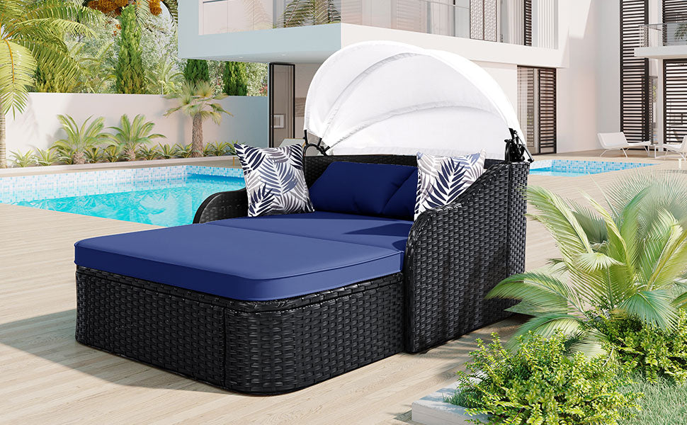 Black wicker outdoor daybed with navy blue cushions and white canopy
