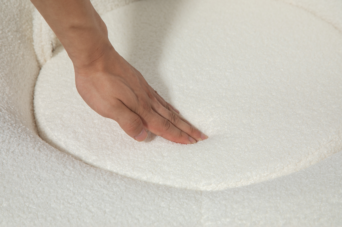 Hand testing the plush softness of an ivory boucle fabric sofa cushion