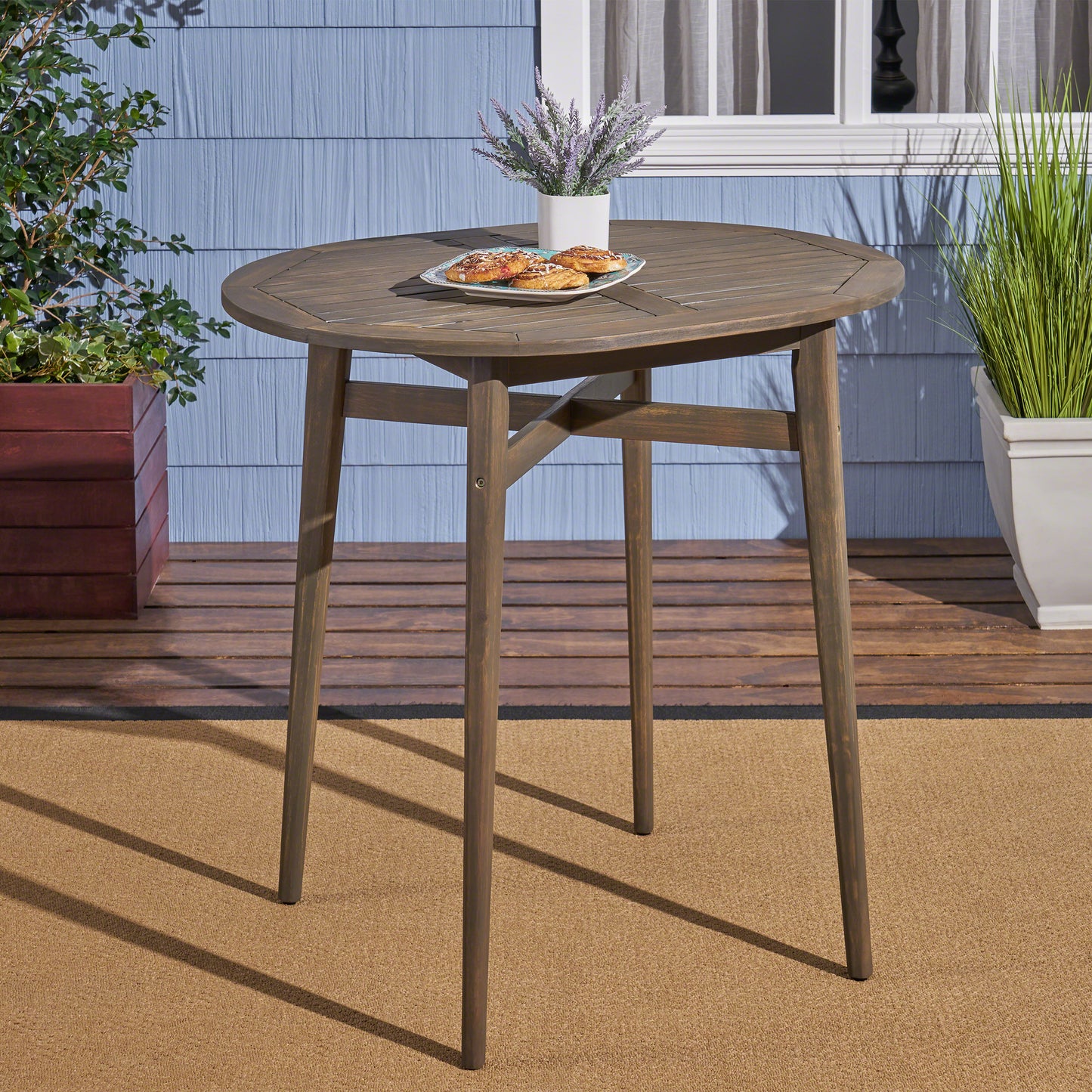 Round wooden bistro table with a natural wood finish and slatted top