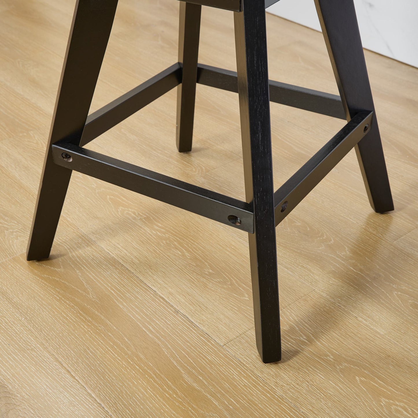 Black wooden bar stool legs on a light wood floor
