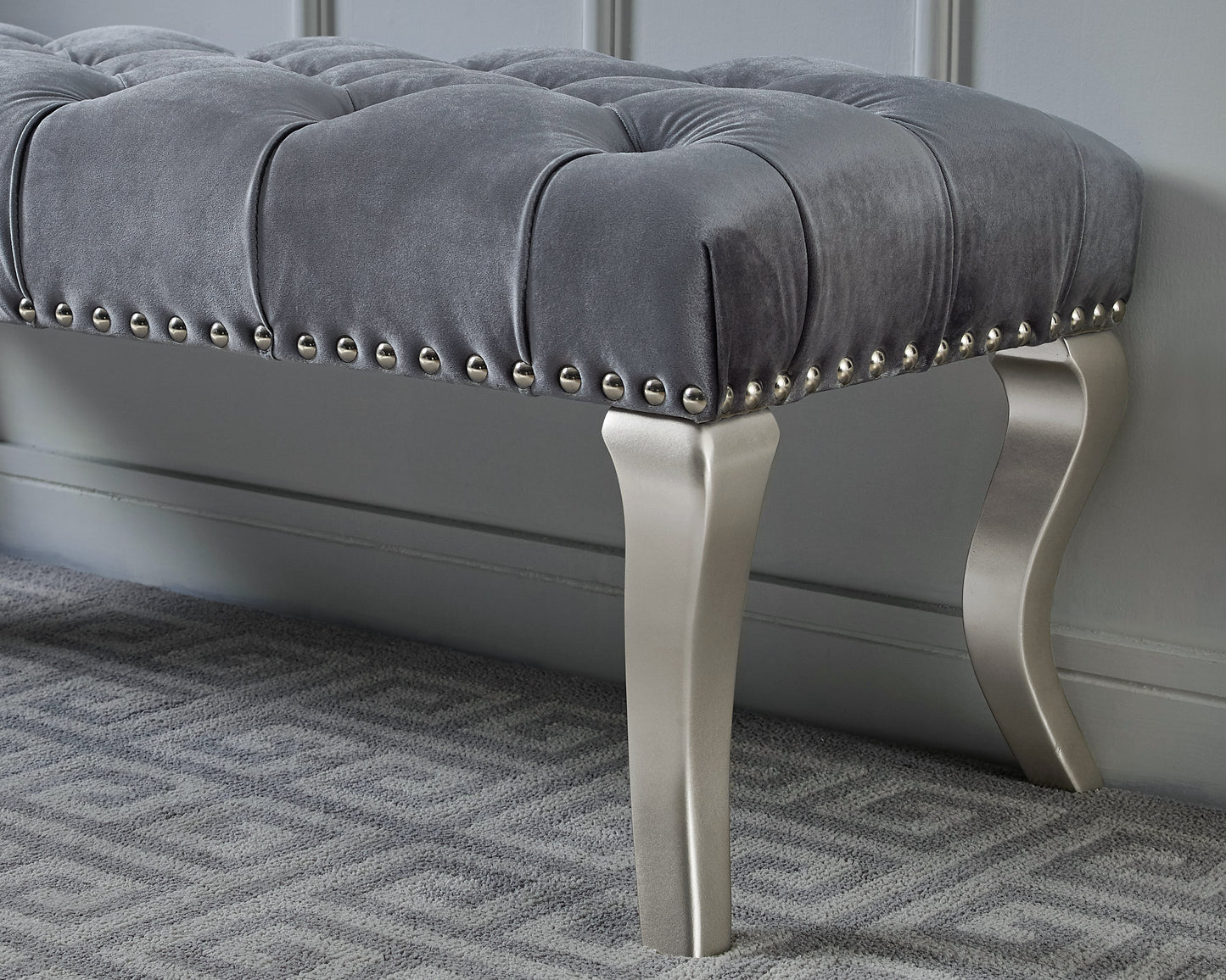 Tufted grey velvet bench with silver nailhead trim and elegant metal legs