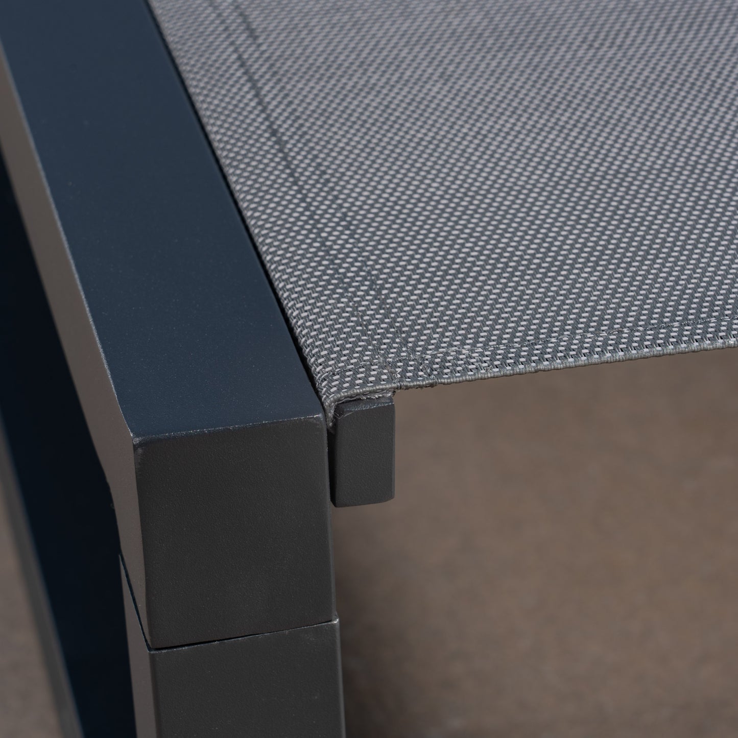 Closeup of dark gray aluminum frame with woven grey textile seat detail
