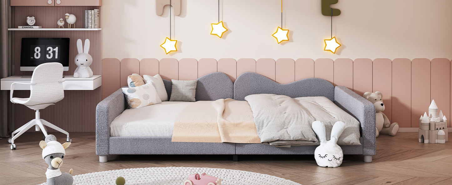 Gray upholstered toddler daybed with plush bedding and playful pillows