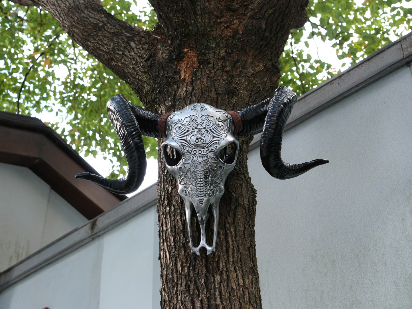 Silver bull skull wall decor with intricate tribal carvings and large black horns