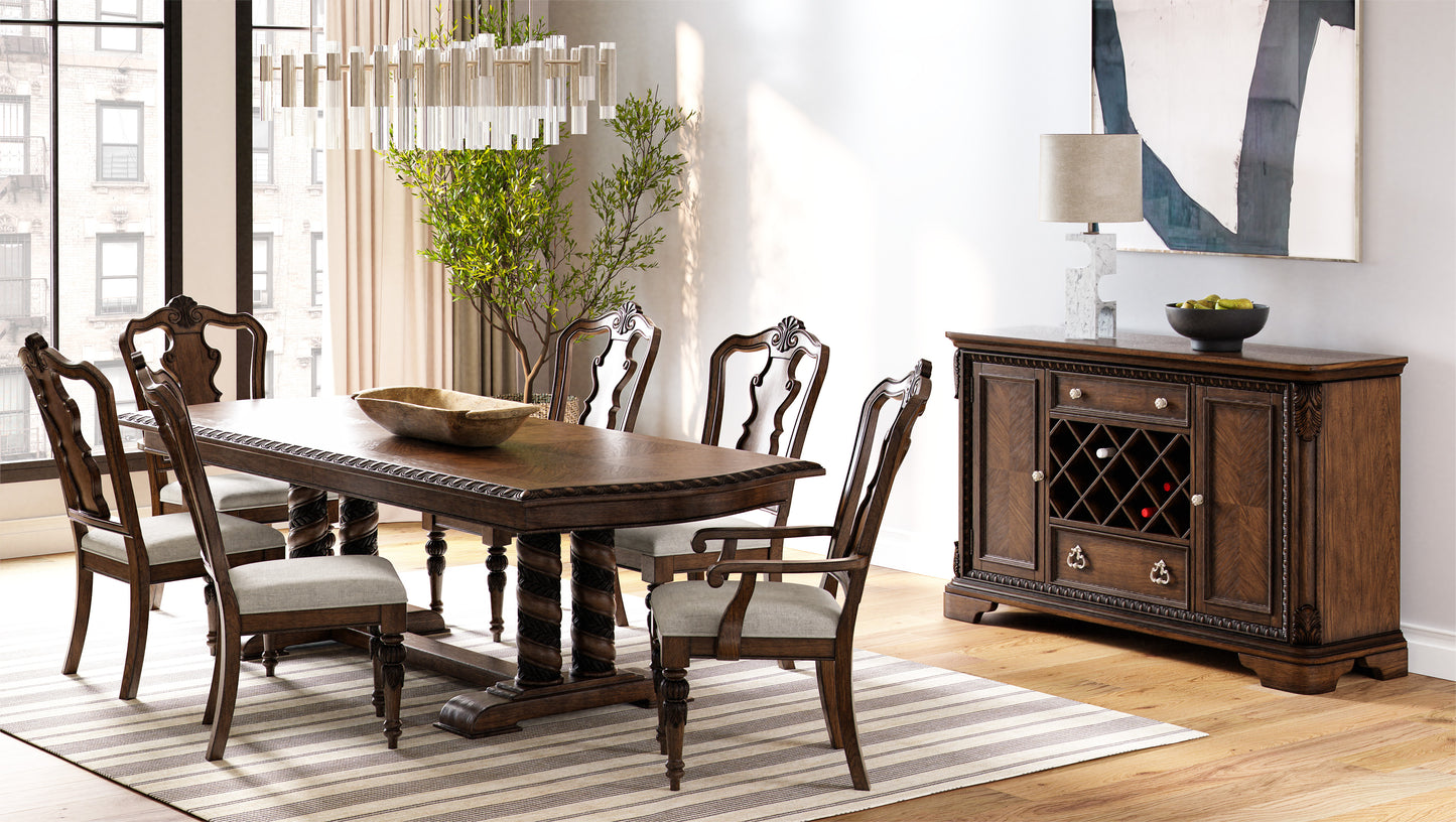 Ornate dark wood dining table with upholstered chairs and a matching buffet