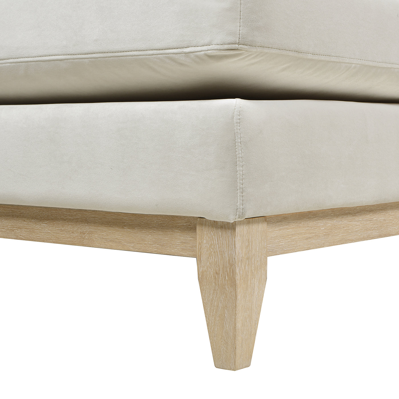 Closeup of a light beige velvet sofa corner with tapered wooden legs