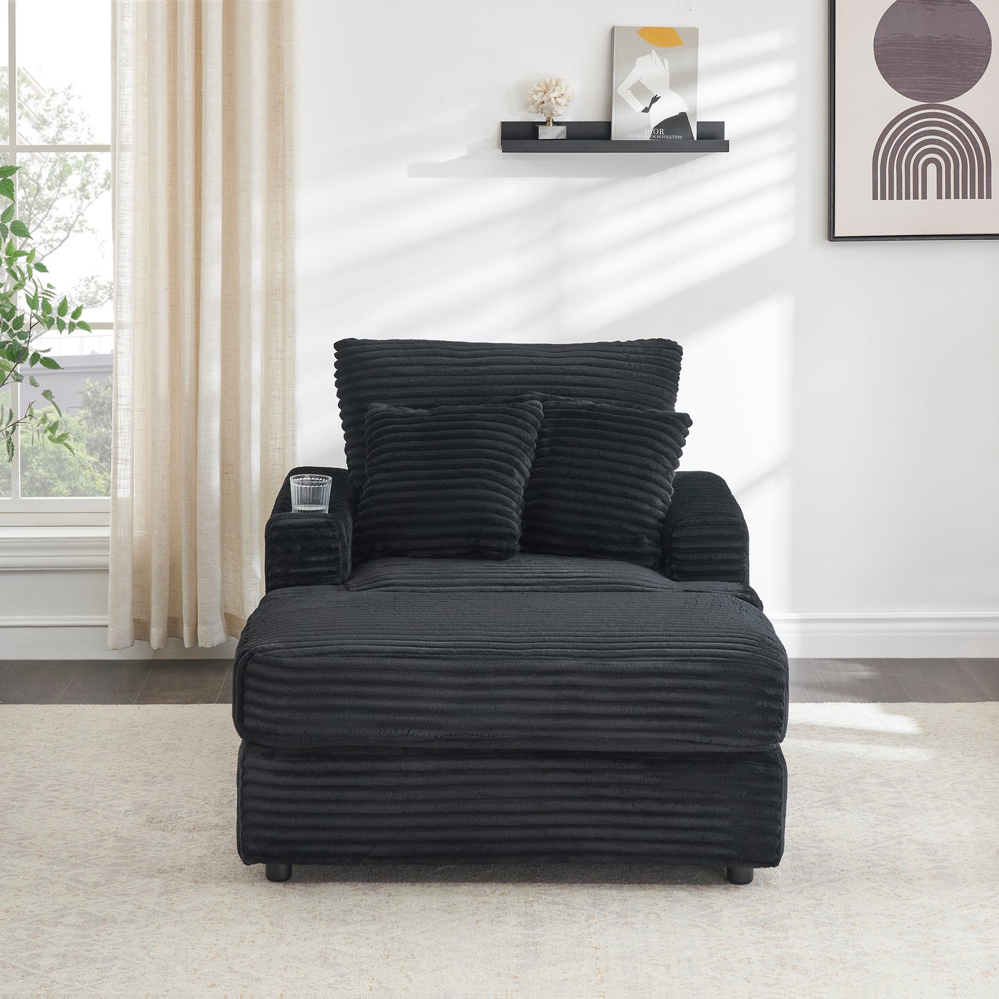 Black corduroy chaise lounge with plush pillows and integrated cup holder