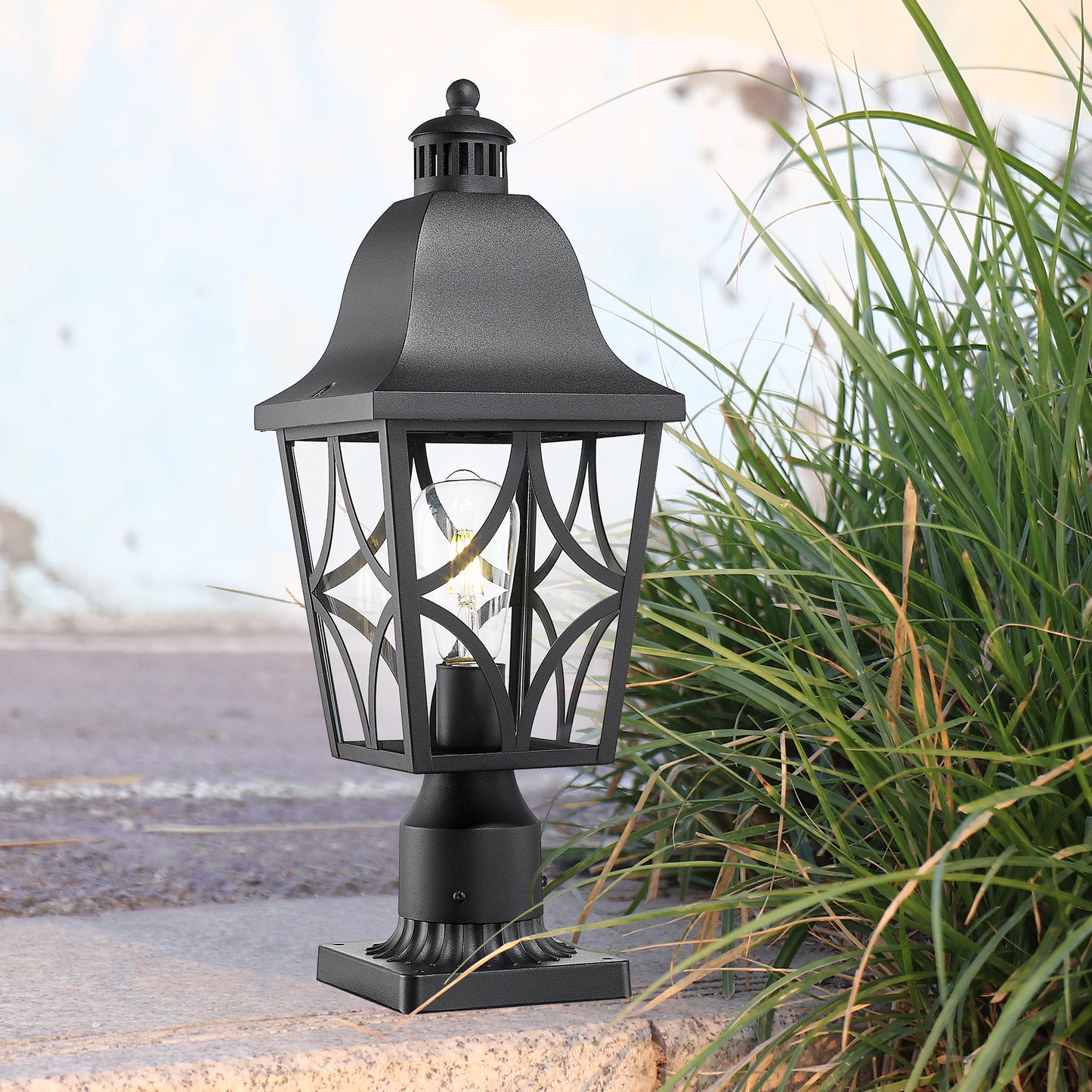 Black metal post lantern with clear glass panes and decorative scrollwork