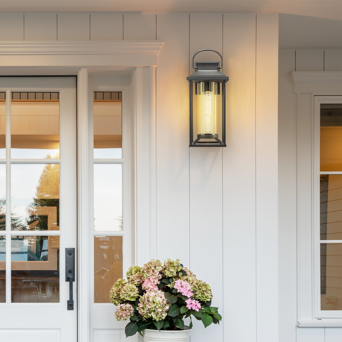 Black metal exterior lantern with clear glass cylinder and exposed filament bulb