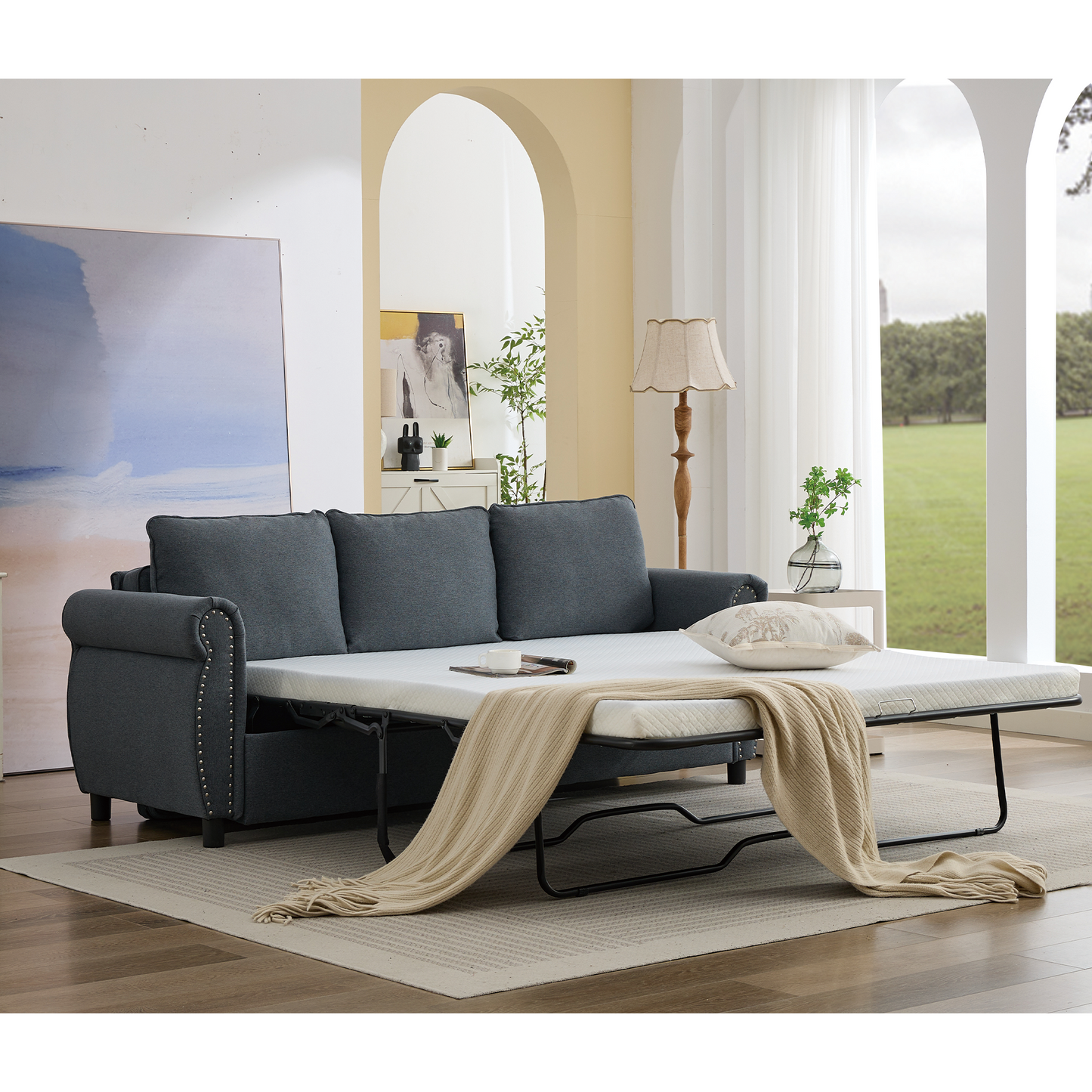 Dark gray fabric sofa bed with rolled arms and nailhead trim
