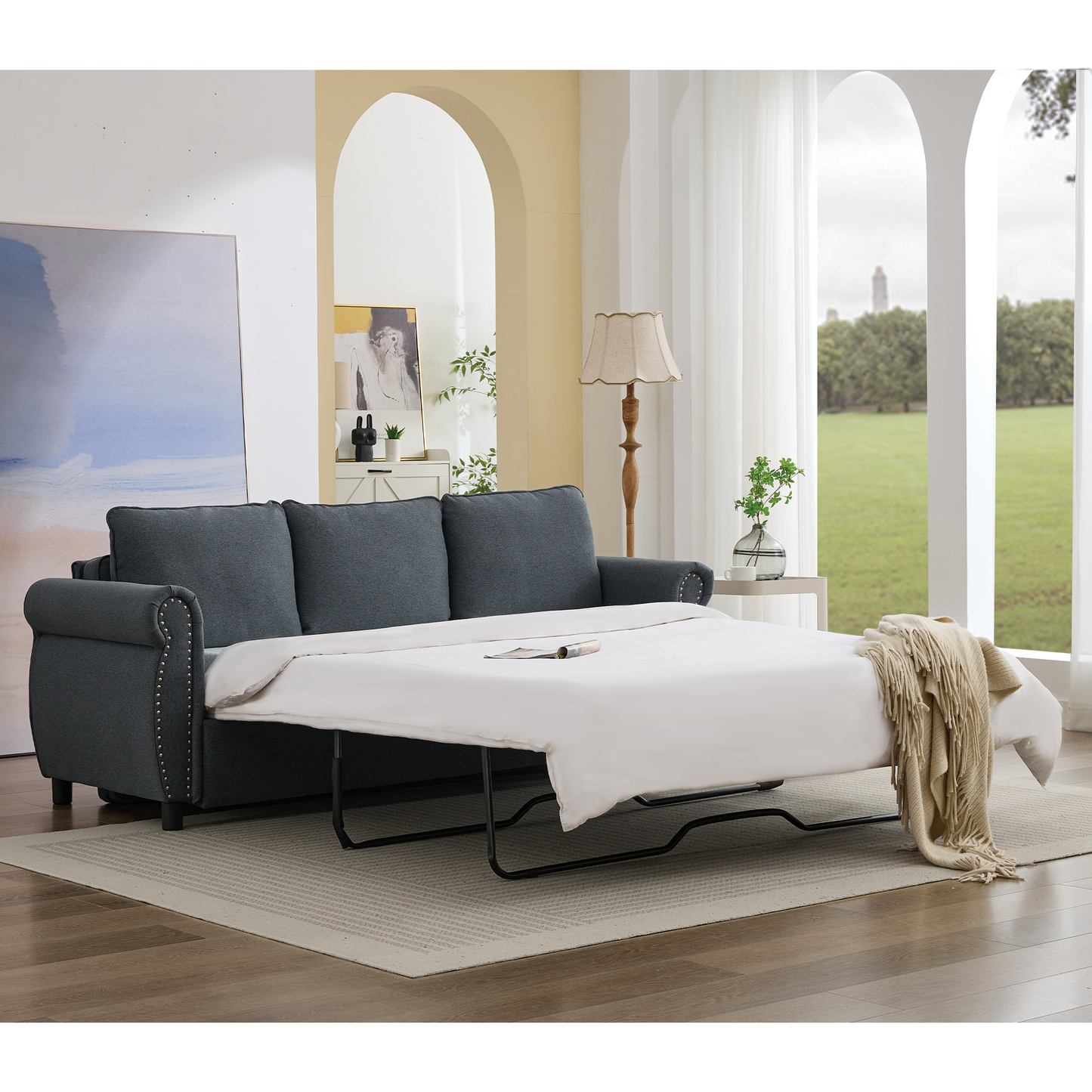 Dark grey tufted sofa bed pulled out with white linens beige throw blanket
