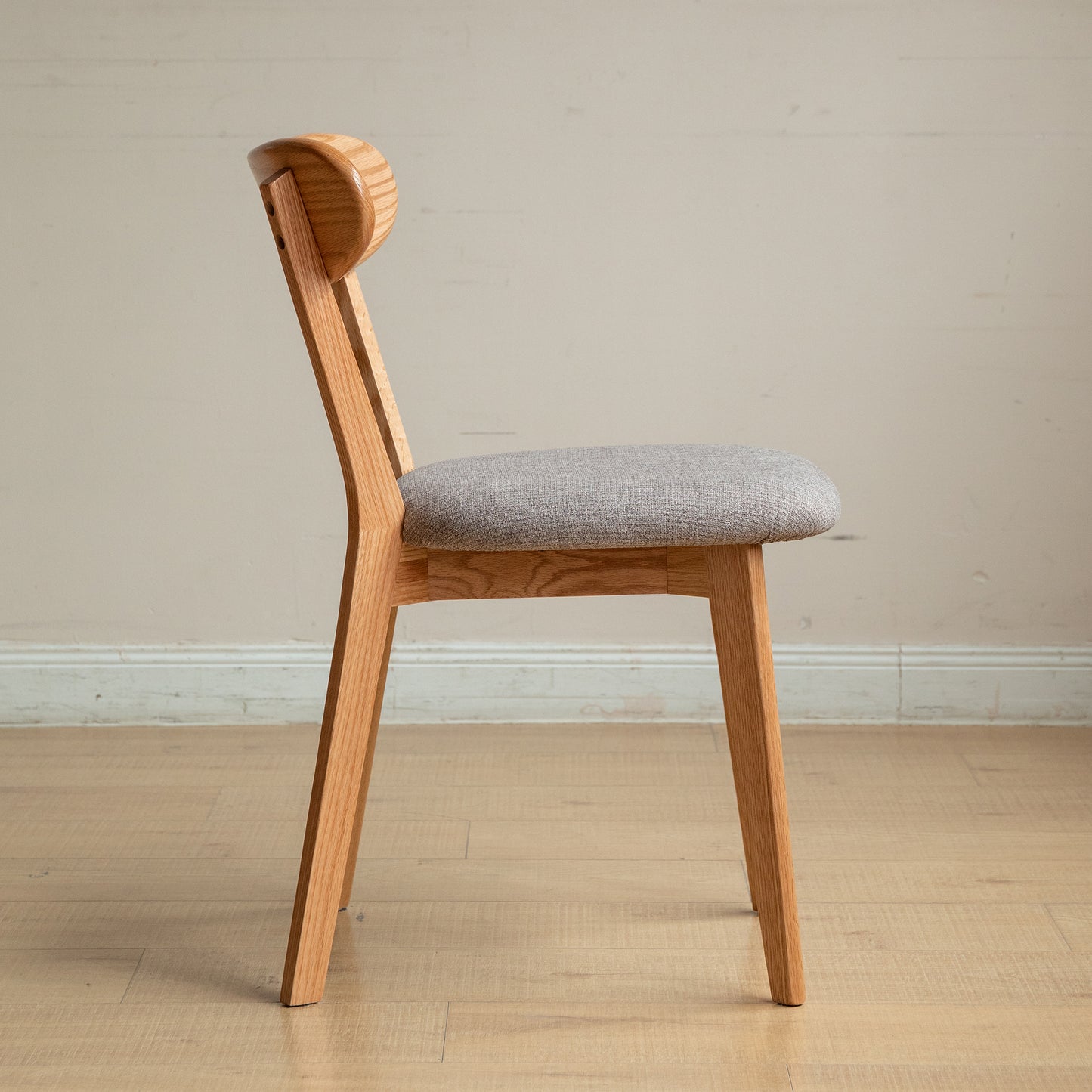 Wooden dining chair with light grey fabric seat and curved backrest