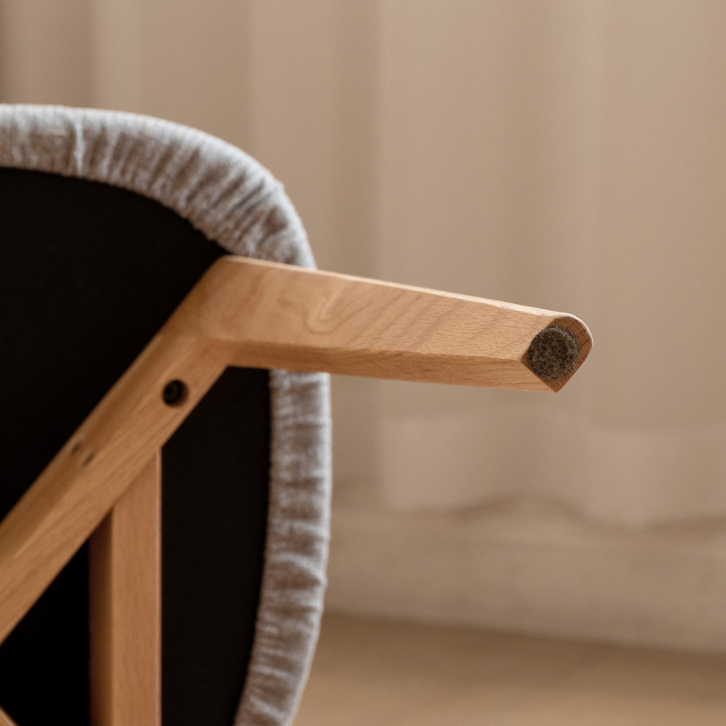 Light grey fabric upholstered chair seat edge and natural wood leg detail