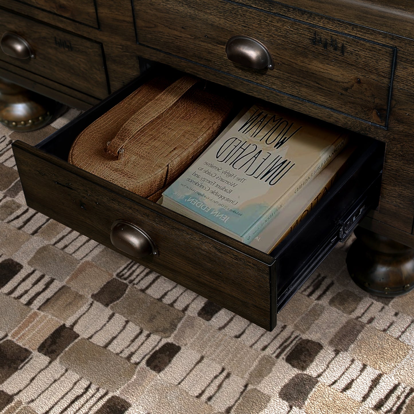 Dark wood dresser drawer with books and a textured case
