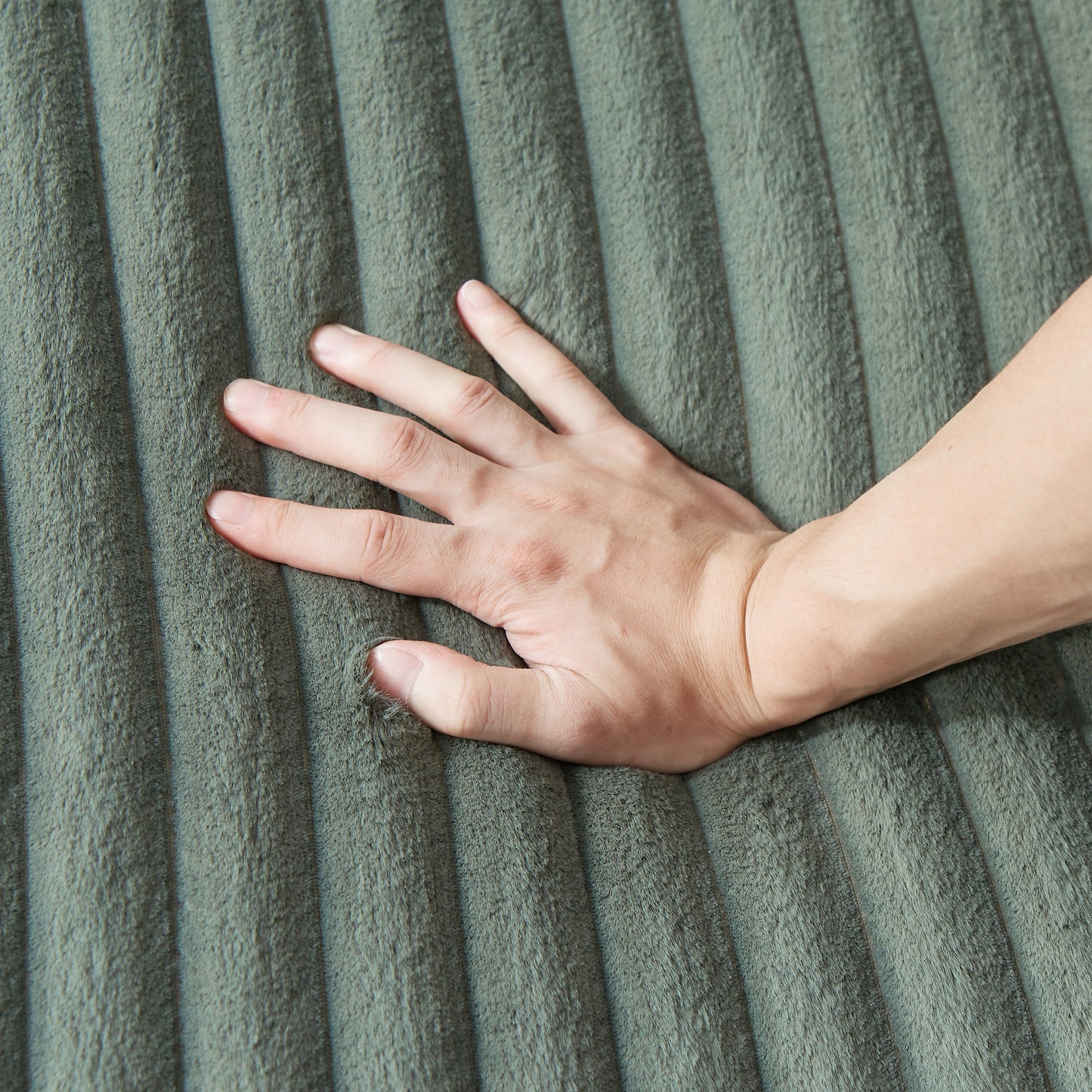 Closeup of a hand pressing into a plush olive green corduroy fabric Tactile upholstery