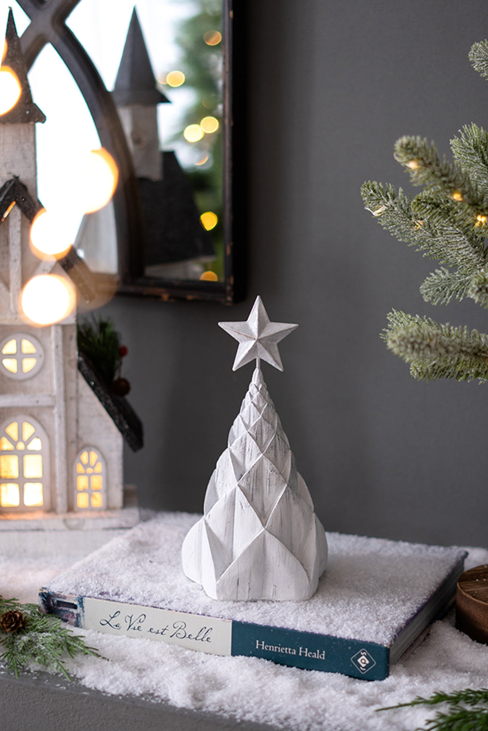White conical Christmas tree decoration with star topper on faux snow