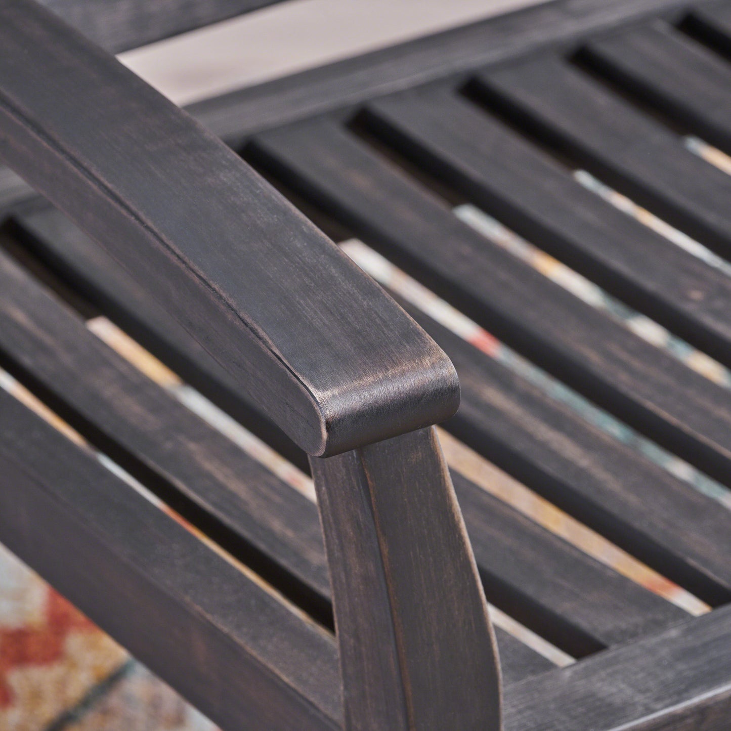 Dark brown wooden patio chair armrest showing slatted design