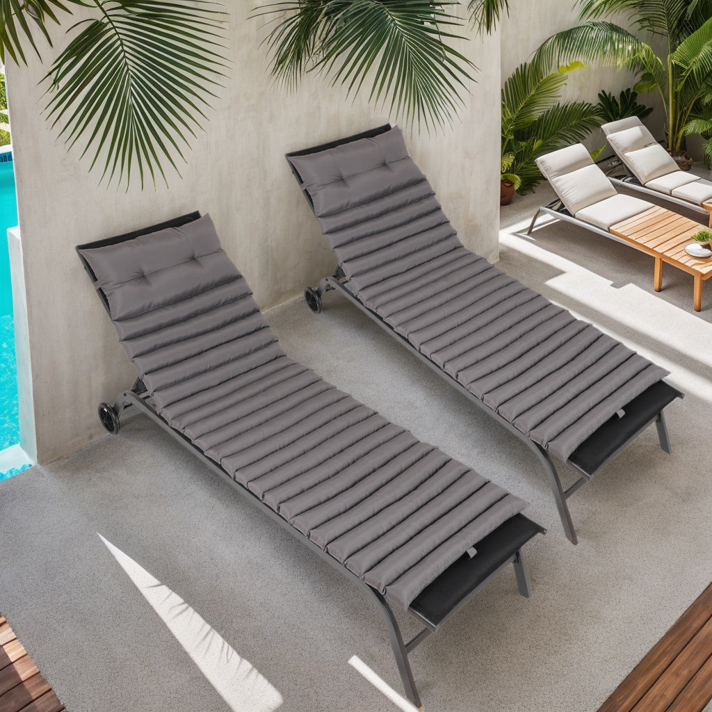 Two grey padded chaise lounge chairs by a pool perfect for outdoor relaxation
