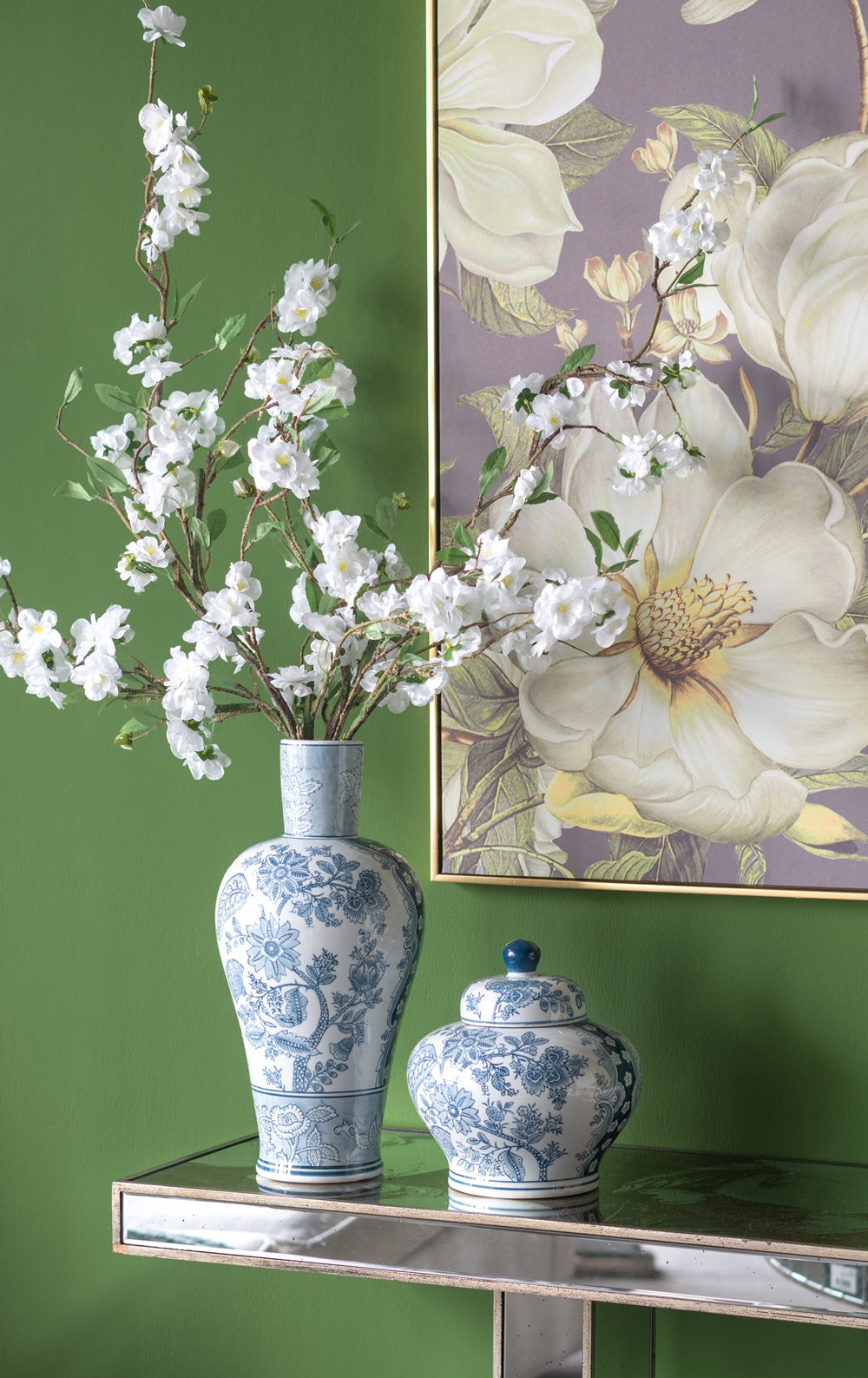 Tall blue and white ceramic vase with floral pattern holding white cherry blossoms